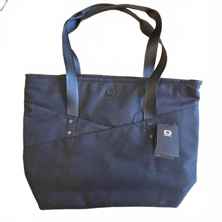 A black canvas tote bag with black shoulder straps, featuring a diagonal stitched detail and a hanging brand tag on a white background.